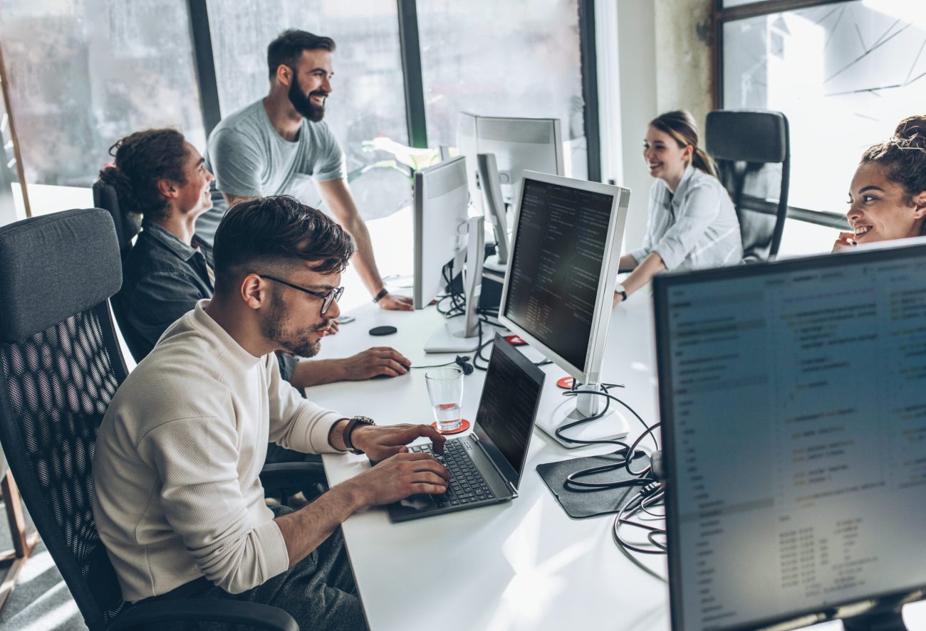 Image of a team of analysts conversing around a table with computers.